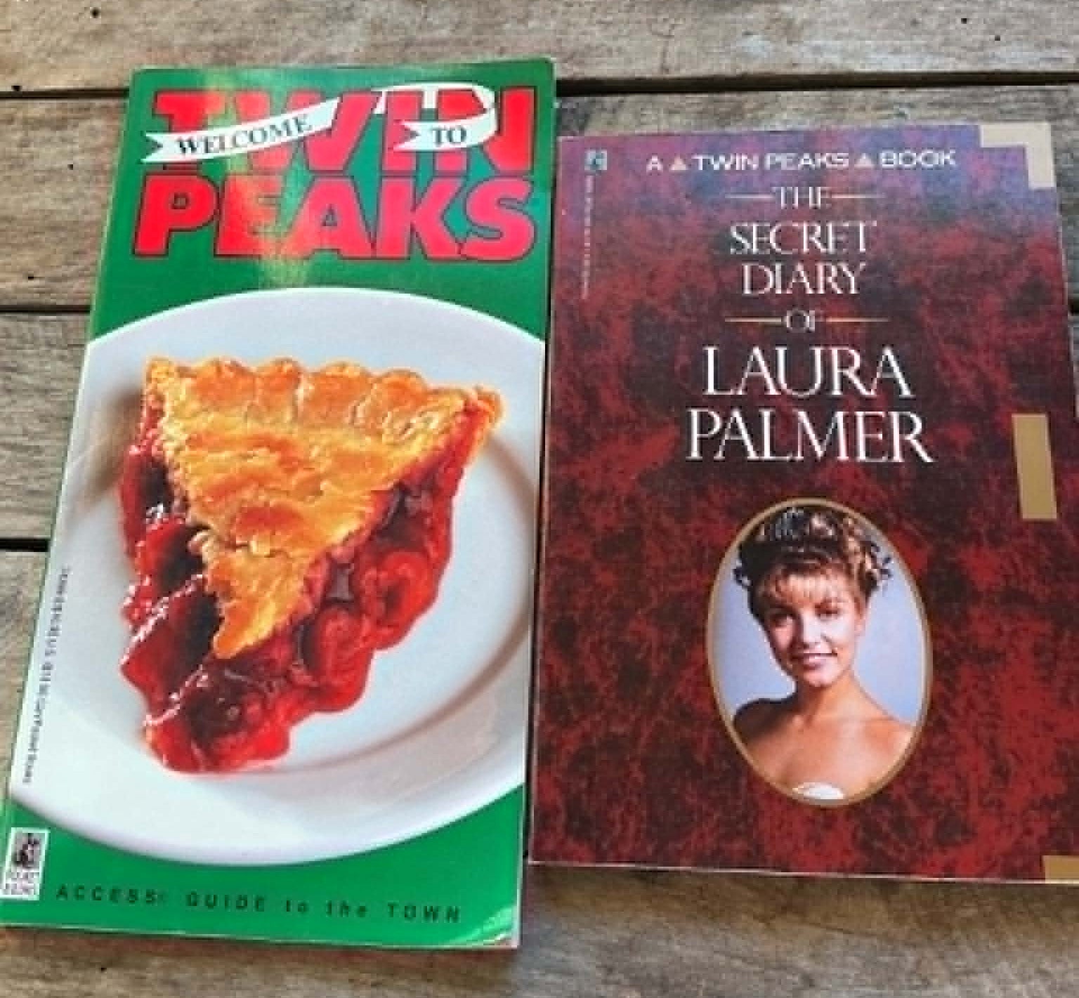 Two books on a wooden surface, one titled 'Welcome to Twin Peaks' and the other 'The Secret Diary of Laura Palmer'.